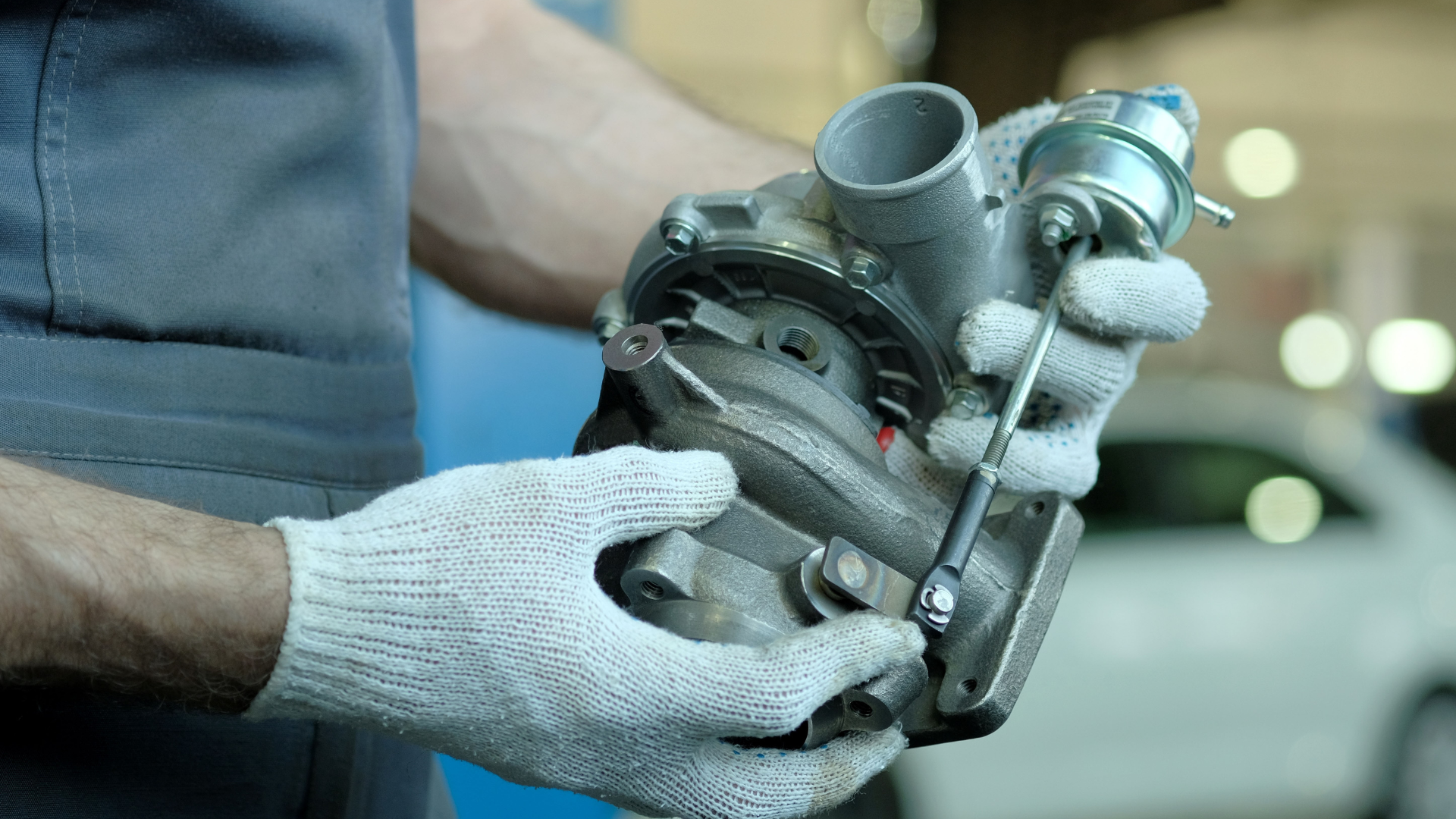 A mechanic holding a turbocharger in his hands
